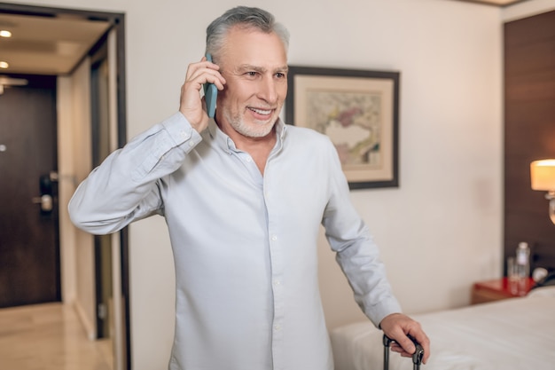 Business talk. Mid-aged gray-haired businessman talking on the phone and looking involved