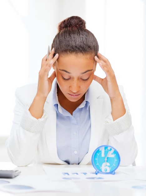 business, tax, deadline concept - african businesswoman working with calculator and clock in office