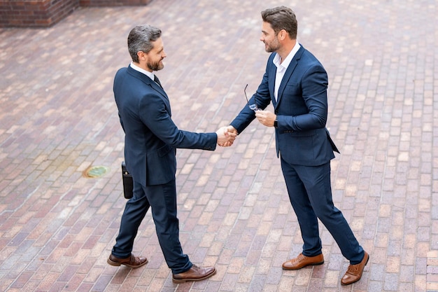 Business team businessman handshake with partner businessmen in suit shaking hands outdoors handshak