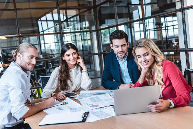 Business team discussing new business project at workplace with papers and laptop in office