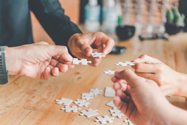 Business team handle a piece of white puzzles that are about to drop to get a complete worksheet - An attempt to succeed.