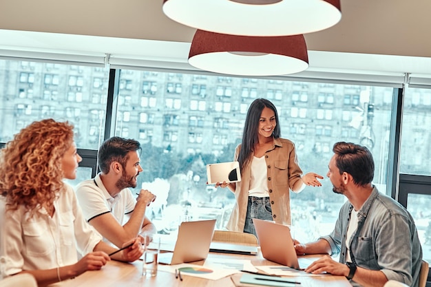 Business team having meeting in conference room Cheerful businesswoman holding digital tablet in hand while talking