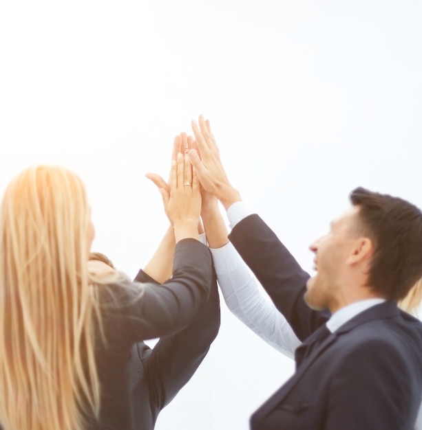 business team standing in a circle and together raised their hands on a white background.