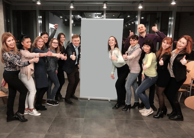 Business team standing in front of a large banner and showing thumb up