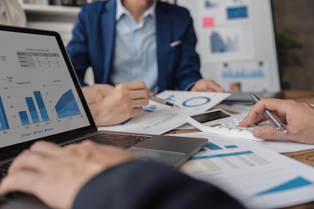 Business team using a calculator to calculate the numbers of statistic business profits growth rate on documents graph data desk in the office teamwork process