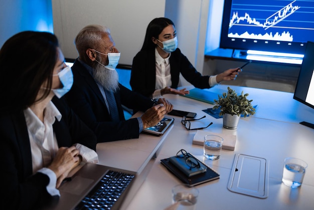 Business teamwork doing meeting inside fintech company office wearing safety mask during coronavirus outbreak  Focus on senior man hands