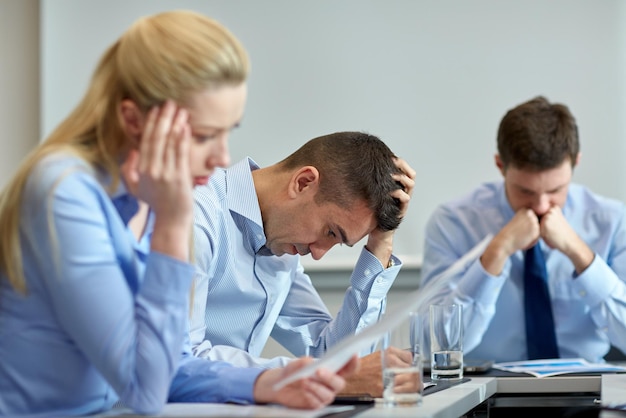 business, teamwork, people and crisis concept - business team sitting sad and solving problem in office