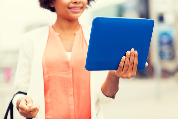 business, technology, communication and people concept - close up of young smiling african american businesswoman with tablet pc computer in city