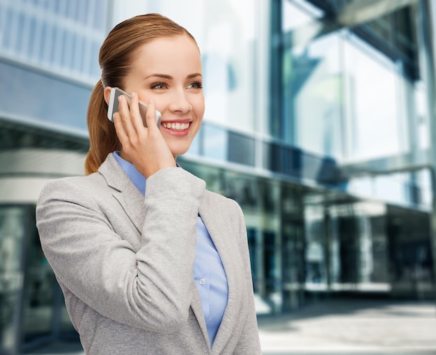 business, technology and education concept - friendly young smiling businesswoman with smartphone