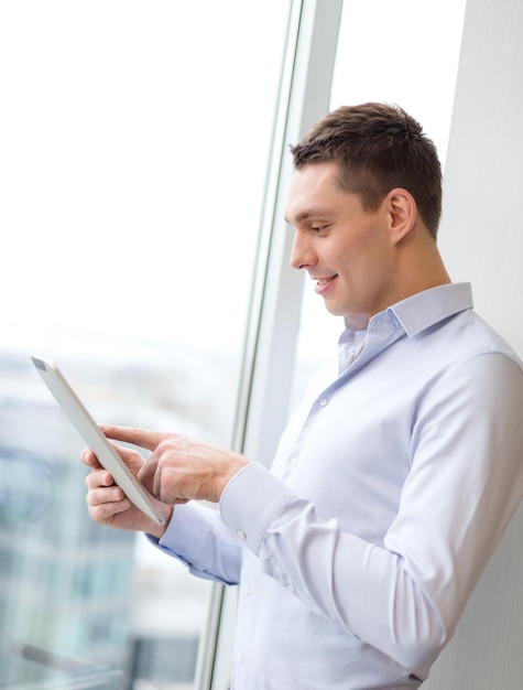 business, technology, internet and office concept - smiling businessman with tablet pc computer in office