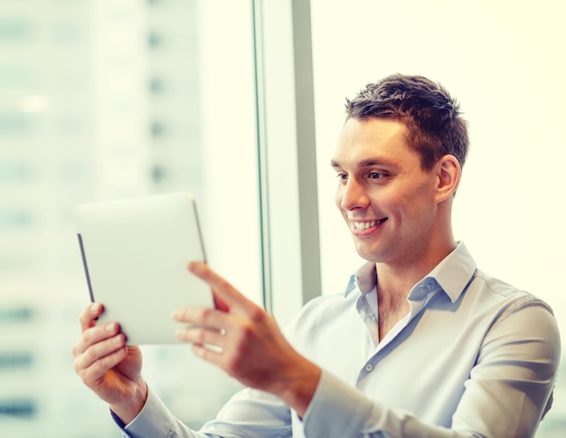 Photo business, technology, internet and office concept - smiling businessman with tablet pc computer in office