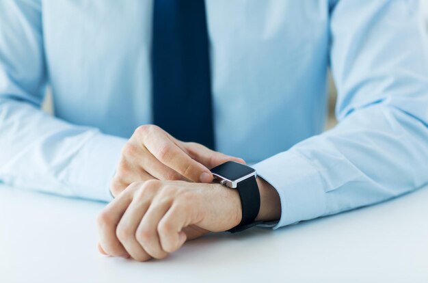 business, technology and people concept - close up of male hands setting smart watch at home