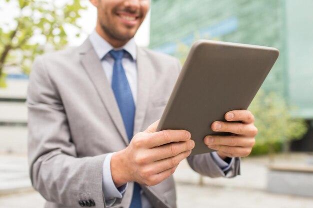 business, technology and people concept - close up of smiling man with tablet pc computer in city