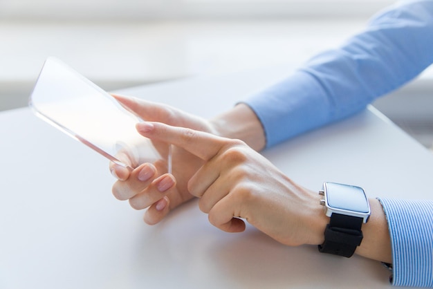 business, technology and people concept - close up of woman hand holding and showing transparent smart phone and watch at office