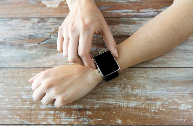 business, technology and people concept - close up of woman hands setting smart watch at home