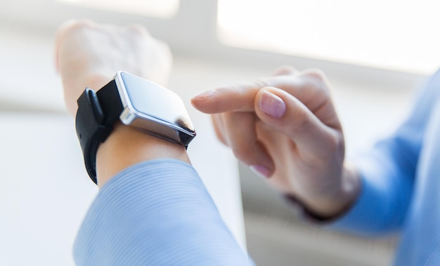 business, technology and people concept - close up of woman hands setting smart watch at office