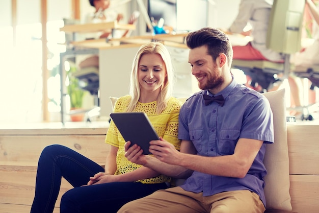 business, technology, startup and people concept - happy creative team with tablet pc computer in office