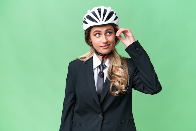 Business Uruguayan woman wearing a helmet biker over isolated background having doubts and with confuse face expression