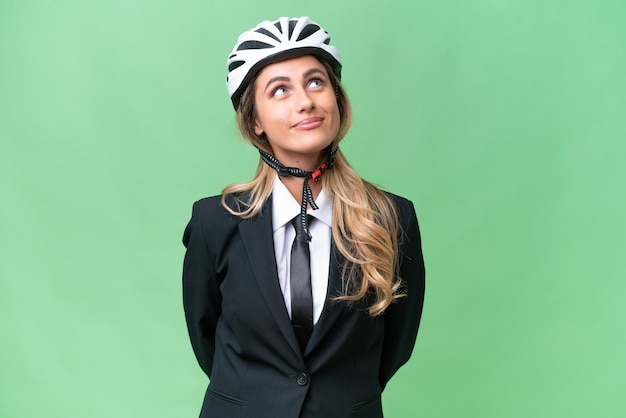 Business Uruguayan woman wearing a helmet biker over isolated background and looking up