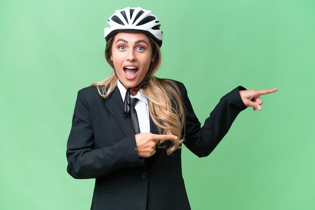 Business Uruguayan woman wearing a helmet biker over isolated background surprised and pointing side