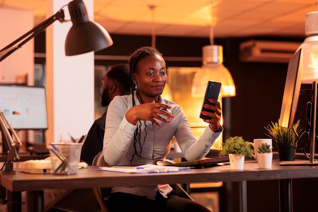 Business woman attending online videoconference meeting on smartphone, talking to people on remote teleconference call with webcam. Using videoconference telework chat on internet.