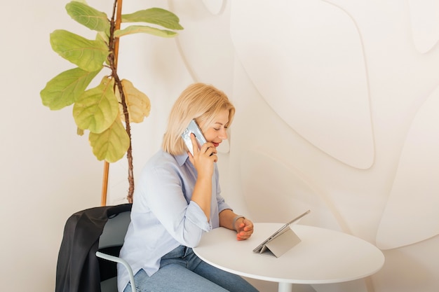 Business woman in a blue shirt working on notebook in a cafe on a white table