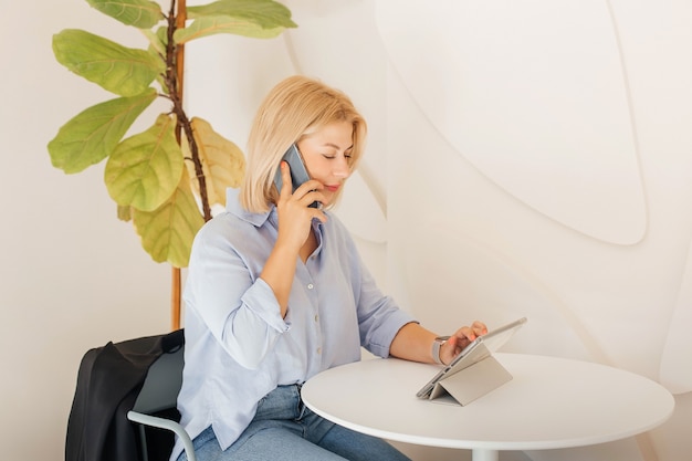 Business woman in a blue shirt working on notebook in a cafe on a white table