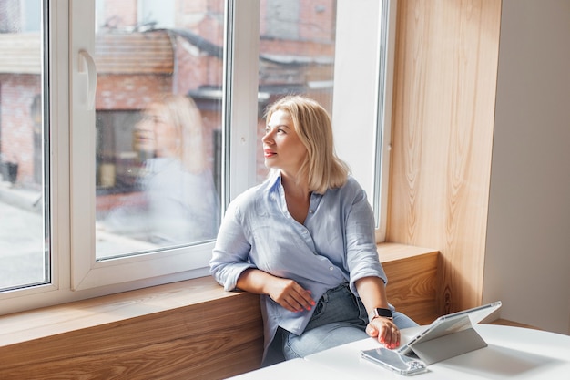 Business woman in a blue shirt working on notebook in a cafe on a white table