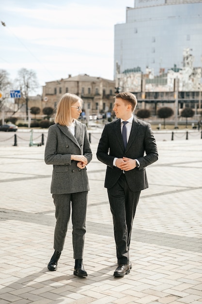 A business woman and a businessman are walking around the city outside the office, planning and discussing a new project with a partner, professionals work in a team