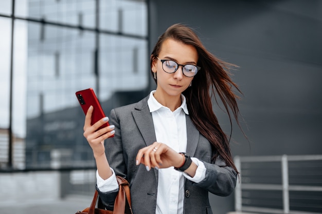 A business woman checks the time in the city during a working day waiting for a meeting. Discipline and timing. An employee goes towards a corporate meeting.