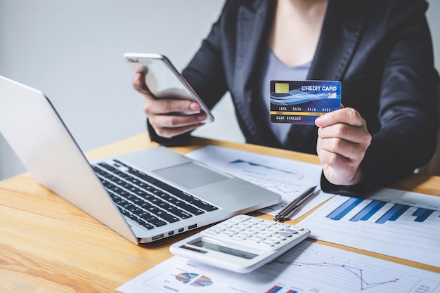 Business woman consumer holding smartphone, credit card and typing on laptop for online shopping and payment make a purchase on the Internet, Online payment, networking and buy product technology