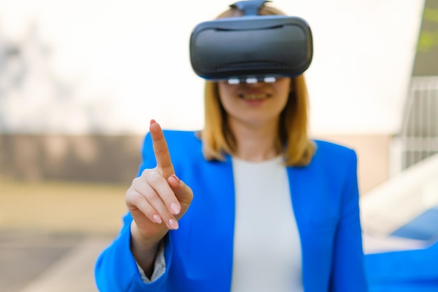 Business woman controls the virtual interface by pressing buttons with her finger in VR goggles