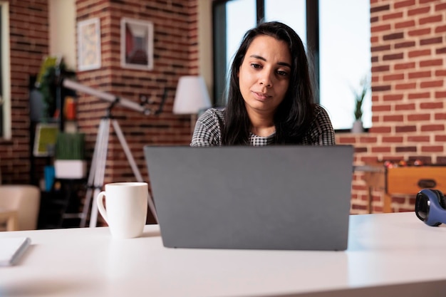 Business woman doing remote online job at home, using laptop to send email and analyze research information. Working on internet report with startup network or attending school class lesson.