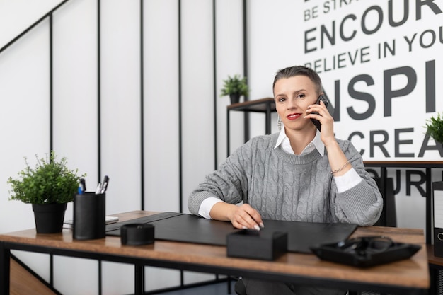 Business woman european appearance with a short haircut speaks on the phone in the office