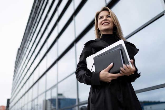 A business woman goes to work with a laptop under her arm and a smile on her face concept of