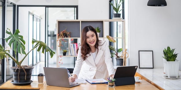 Business woman hand holding pen looking at bank savings account application on laptop account or saving money or insurance concept