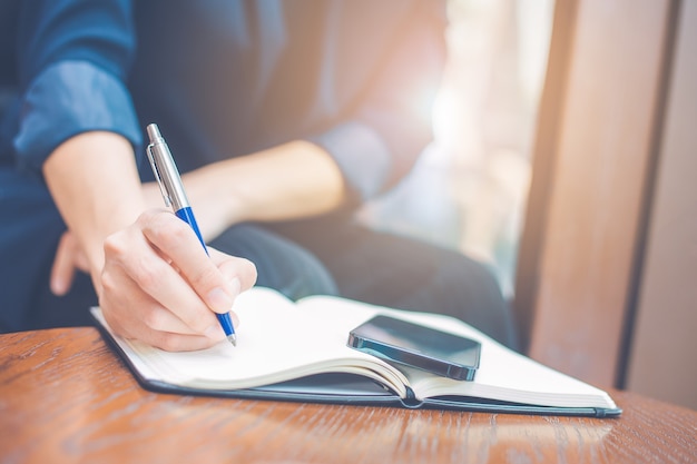 Business woman hand writing on a notepad with a pen in the office.