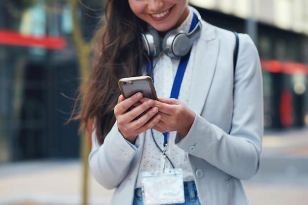 Business woman hands and phone with smile in communication social media or texting in city Hand of female typing and smiling on smartphone for 5G connection mobile app or browsing in networking