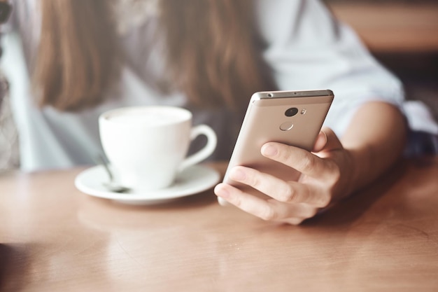 Business woman hands using smart phone and cup of coffee