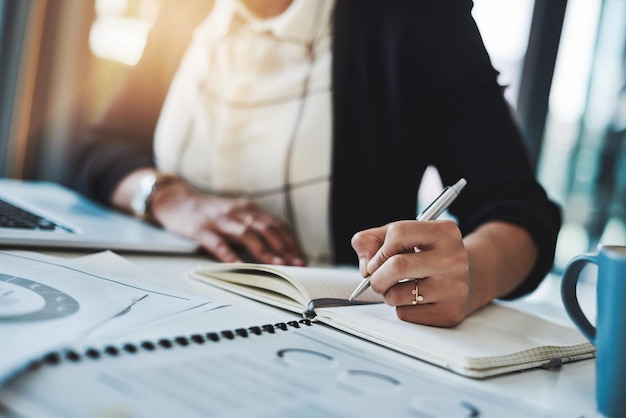 Business woman hands and writing in a office with planning notes and corporate notebook Female person employee and work planner book with company paperwork and charts for professional project