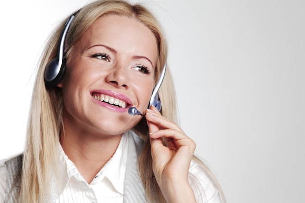 Business woman in a headset on a gray wall