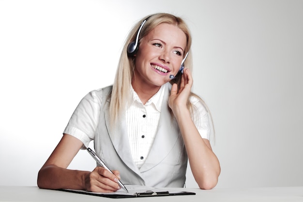 Business woman in a headset writing in notebook