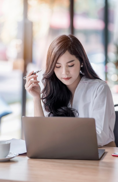  business woman holding pen and looking at laptop