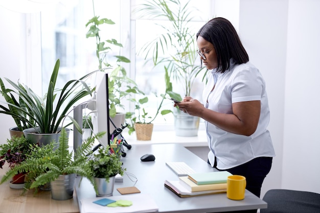 Business woman holding smartphone standingin office black female manager ceo using cell phone mobile...