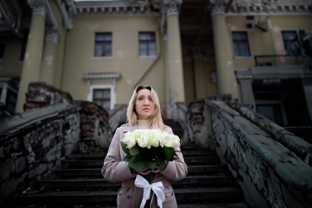 A business woman holds a bouquet of white roses in front of her