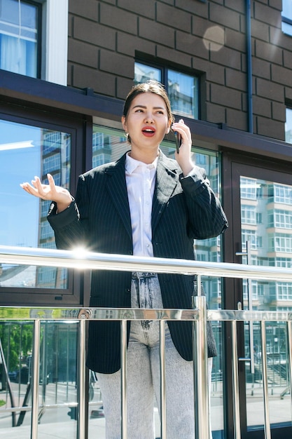 A business woman in a jacket speaks very emotionally on the phone against