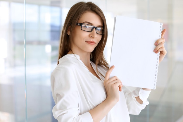 Business woman keeping copy space area while standing in the office