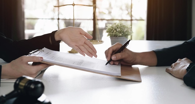 Business woman and lawyers discussing contract papers with brass scale on wooden desk in office Law legal services advice Justice concept