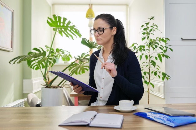 Business woman looking at camera talking holding papers documents in hands