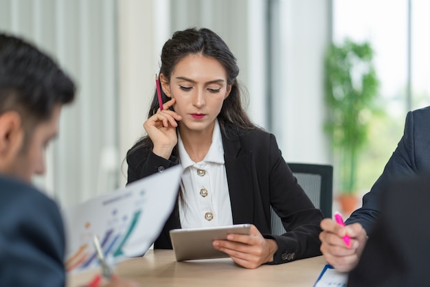 Business Woman looking plan of marketing on tablet while meeting with colleagues at the office